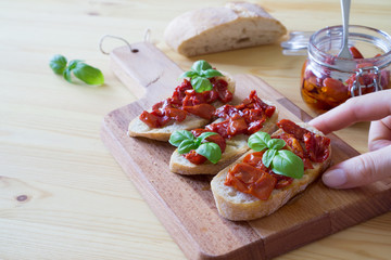 Bruschetta with sun dried fermented tomatoes, green basil and olive oil on italian ciabatta on...