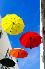 Fototapeta na wymiar Colored umbrellas hang against a blue sky in shopping mall in Waddinxveen