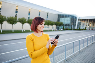 Fototapeta premium Beautiful girl uses a smartphone. View photos and videos on the phone.