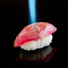 Roasting salmon nigiri by flame jet in a sushi restaurant