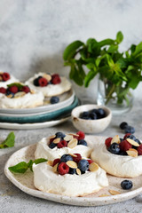 Classic dessert pavlova with cream and berries and almonds on the kitchen table. Portion dessert pavlova.