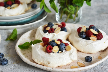 Classic dessert pavlova with cream and berries and almonds on the kitchen table. Portion dessert pavlova.