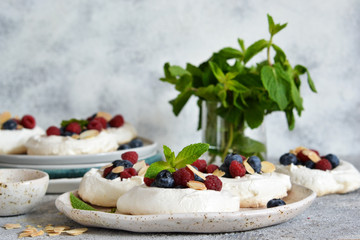 Classic dessert pavlova with cream and berries and almonds on the kitchen table. Portion dessert pavlova.