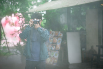 Asian male photographer holding old vintage film camera with light mist in the morning