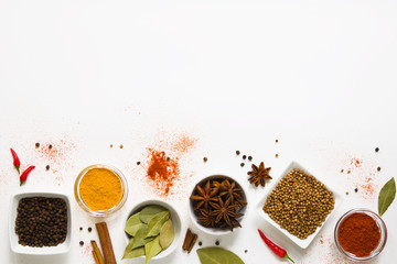 set of assorted colorful spices in white bowls on a white background, flat lay, top view, with copy spice