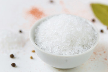 salt in white bowl and colorful spices on a white background