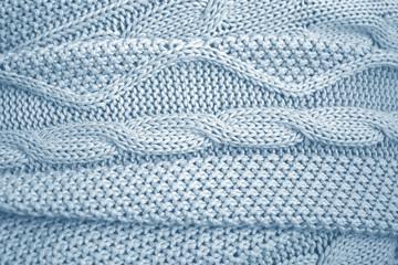 Blue knitted blanket or plaid with a braid pattern. The knitted fabric, soft and warm, wrinkled. Texture for background.