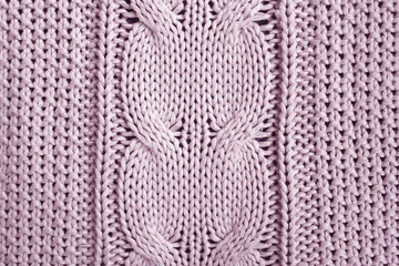 Rose knitted plaid with braid pattern. Close-up photo top view. Home background.
