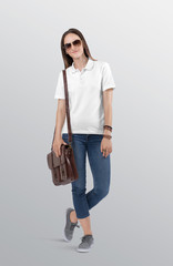 Standing beautiful woman model wearing white plain polo t shirt in blue denim jeans pant. Carrying brown office bag on her shoulder. Isolated background