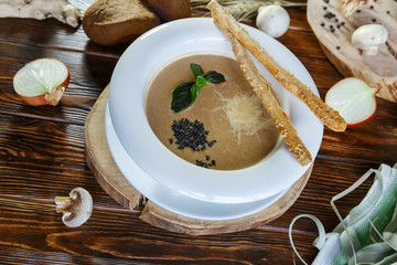 Mushroom soup with pasta with champignons and herbs on a brown wooden background
