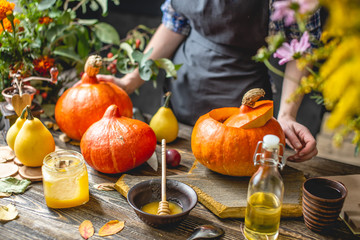 Obraz na płótnie Canvas Orange pumpkins for baking with honey and cinnamon on wooden table background. Concept autumn food
