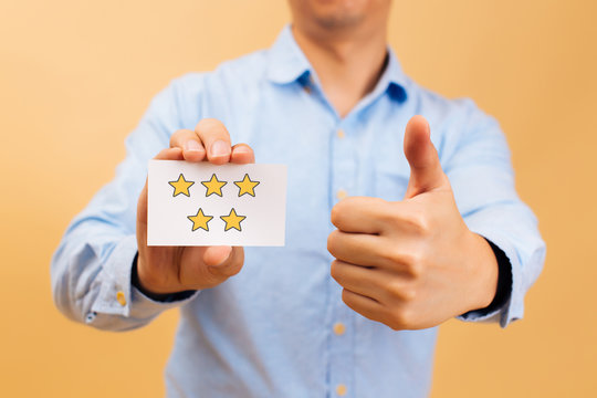 Businessman showing five yellow stars card and thumbs up in bright color background. Review, rating, ranking and evaluation concept