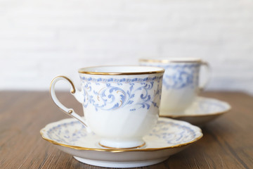 木製テーブルの上に乗った白い陶器のカップ&ソーサーにブラックコーヒー