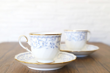 木製テーブルの上に乗った白い陶器のカップ&ソーサーにブラックコーヒー