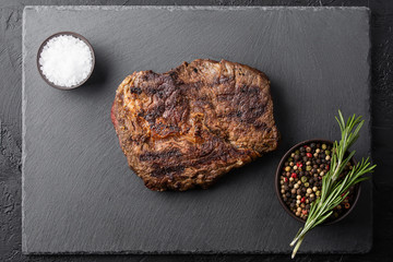 fried steak on black plate with spices on black table