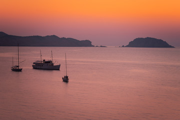 Boats seeing the sunset at August in Cavalleria beach at the north coast of Menorca, Spain.