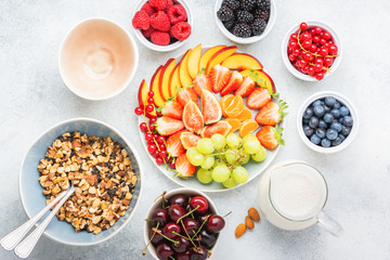 Raw paleo granola or muesli made from nuts. Fruit berries platter, strawberries blueberries raspberries peach figs red currant, top view, selective focus