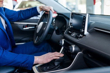 Male hands on steering wheel, car interior