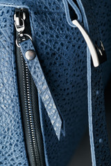 Lock and buckle close-up, elements of a blue backpack made of genuine leather on a dark background, handmade.