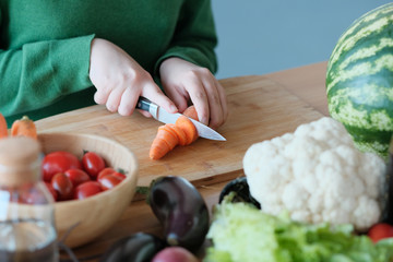 girl cuts a carrot with a knife to make a salad. 