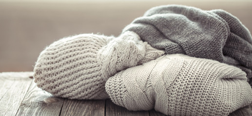 A cozy stack of knitted sweaters on a wooden background.