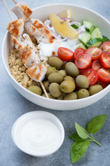 Close-up of greek souvlaki bowl with quinoa, green olives, vegetables and tzatziki sauce, studio shot
