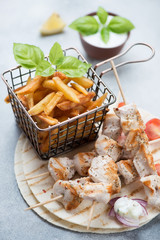 Close-up of greek chicken souvlaki with french fries and tzatziki, vertical shot