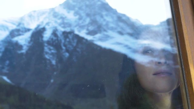 woman at a ski chalet admires mountains window in Chamonix France slowmotion
