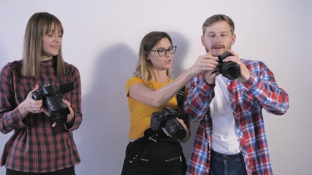 young professionals with digital cameras in their hands discuss pictures made during a seminar for photographers in a photo studio