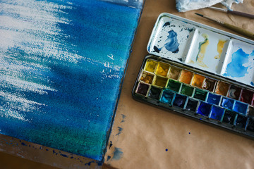Artist paint brushes and watercolor paintbox on plastic palette.