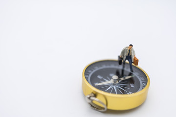 Business Trip, Planning and Direction Concept.  Close up of businessman miniature people with handbag and suitcage walking on compass on white background and copy space.