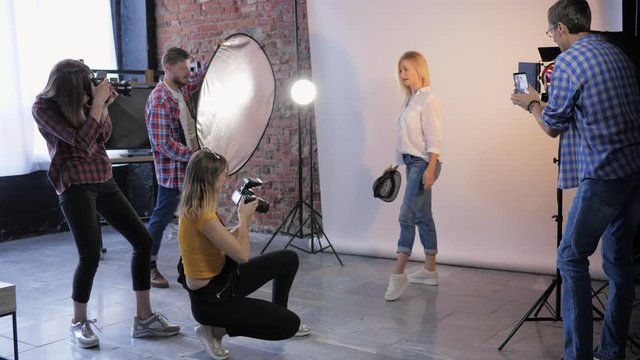 fashion professionals with SLR cameras shoot photos during seminar for photographers in photo studio with beautiful model