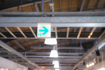 Fototapeta premium an emergency exit sign hanging under a steel beam with blurred background