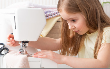 little girl carefully working with modern sewing machine