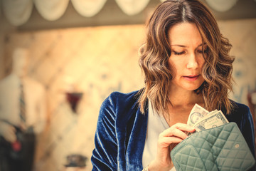 woman counting cash in her wallet - obrazy, fototapety, plakaty
