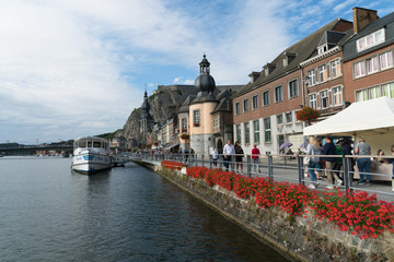 Obraz premium tourists enjoying an evening walk along the Meuse river in the historic old town of Dinant in Belgium