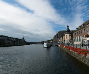Obraz premium tourists enjoying an evening walk along the Meuse river in the historic old town of Dinant in Belgium