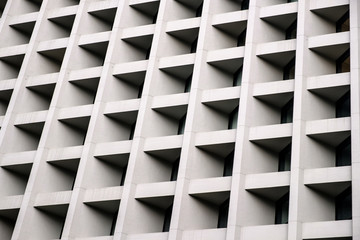 Gray concrete wall with many equal square windows. Abstract city architecture background.