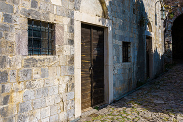 Fototapeta na wymiar paved stone and wall of the building with windows and a door in the medieval fortress