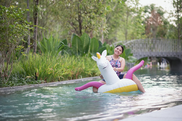 Asian women are enjoying the holidays sitting together on an inflatable pony in the swimming pool.