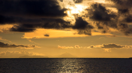 Ocean at sunset with orange sky and black clouds