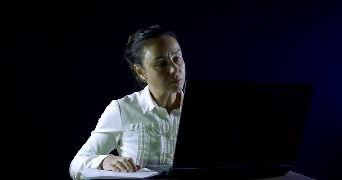 Business woman working late at night in the office on a laptop and parses the current documents