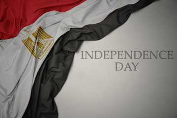 waving colorful national flag of egypt on a gray background with text independence day.
