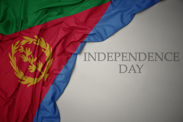 waving colorful national flag of eritrea on a gray background with text independence day.