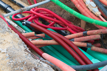 road work construction with many colorful tubes and pipes running through an unconvered ditch