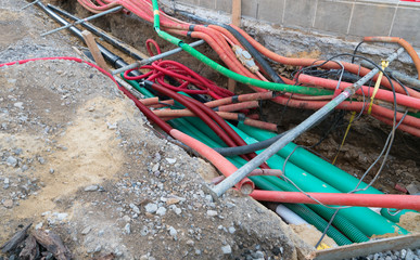 road work construction with many colorful tubes and pipes running through an unconvered ditch