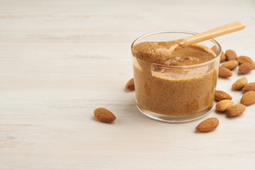 almond butter, raw food paste made from grinding almonds into nut butter, crunchy and stir, white wooden table, copy space