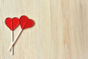two red  heart shaped lollipops on wooden background