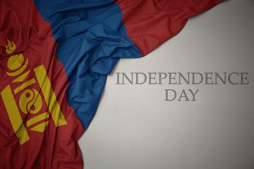 waving colorful national flag of mongolia on a gray background with text independence day.