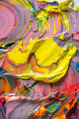 Different bright colors of oil paints are mixed on a palette close-up.